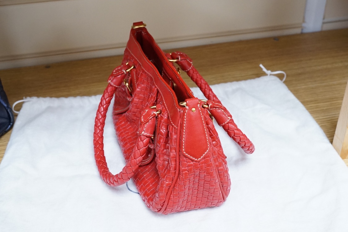 A Prada red braided leather handbag with shoulder strap, authenticity card and dust cover, 25cm wide, Provenance: Purchased by the vendor in Selfridges